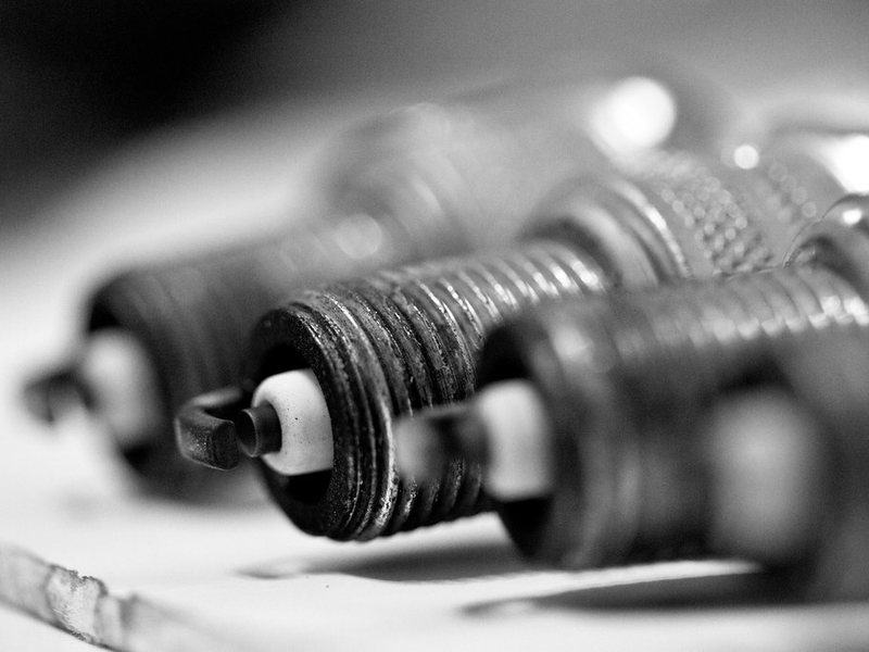 A close-up of new spark plugs lined up on a workbench